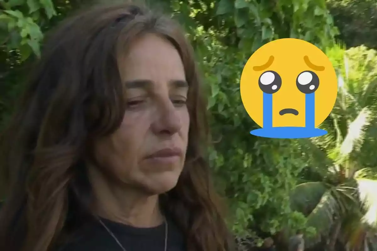 Carmen Alcayde amb expressió trista en un entorn natural al costat d’un emoji gran de carona plorant