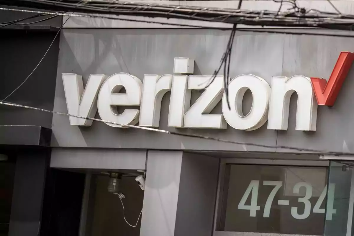 Un letrero de Verizon en la fachada de un edificio con cables eléctricos visibles en la parte superior. Un letrero de Verizon en la fachada de un edificio con cables eléctricos visibles en la parte superior.