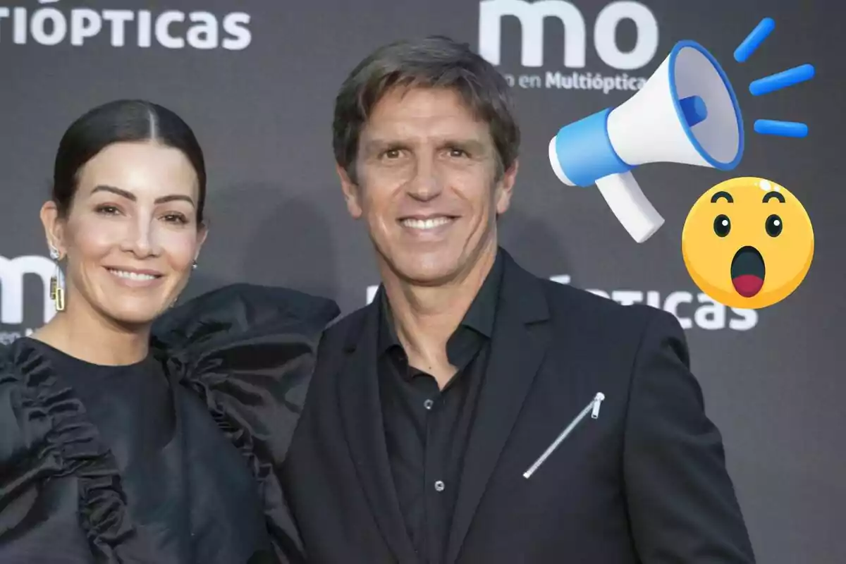 Virginia Troconis i Manuel Díaz somrient posen en un esdeveniment amb un fons de logotips i emojis de megàfon i cara sorpresa.