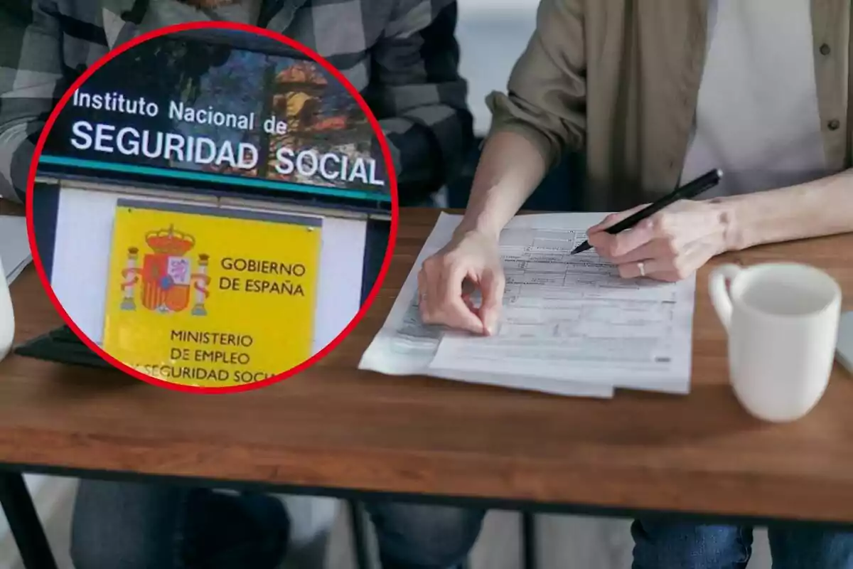 Dues persones revisen documents en una taula, amb una tassa de cafè al costat, i un requadre mostra un cartell de l?Institut Nacional de Seguretat Social del Govern d?Espanya.