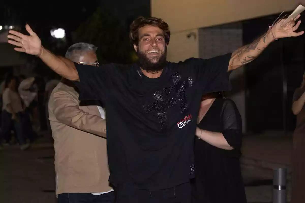 Montoya somriu amb els braços oberts en un carrer de nit envoltat d’altres persones. Montoya somriu amb els braços oberts en un carrer de nit envoltat d’altres persones.