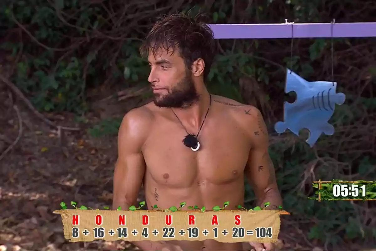 Montoya sense camisa amb barba i tatuatges està dret en un entorn selvàtic amb un trencaclosques penjant i un cronòmetre que marca 05:51 a Supervivientes. Montoya sense camisa amb barba i tatuatges està dret en un entorn selvàtic amb un trencaclosques penjant i un cronòmetre que marca 05:51 a Supervivientes.