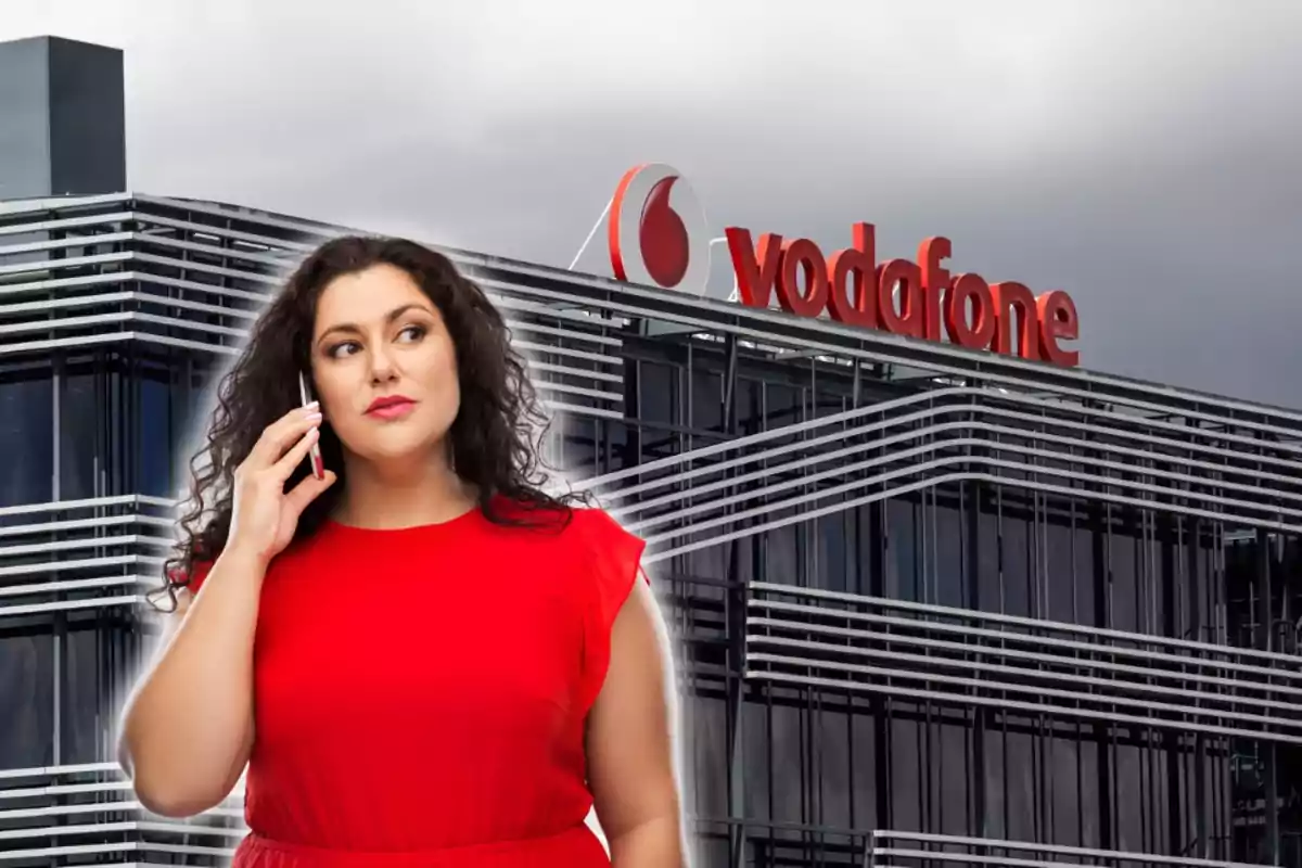 Dona amb vestit vermell parlant per telèfon davant d'un edifici de Vodafone.