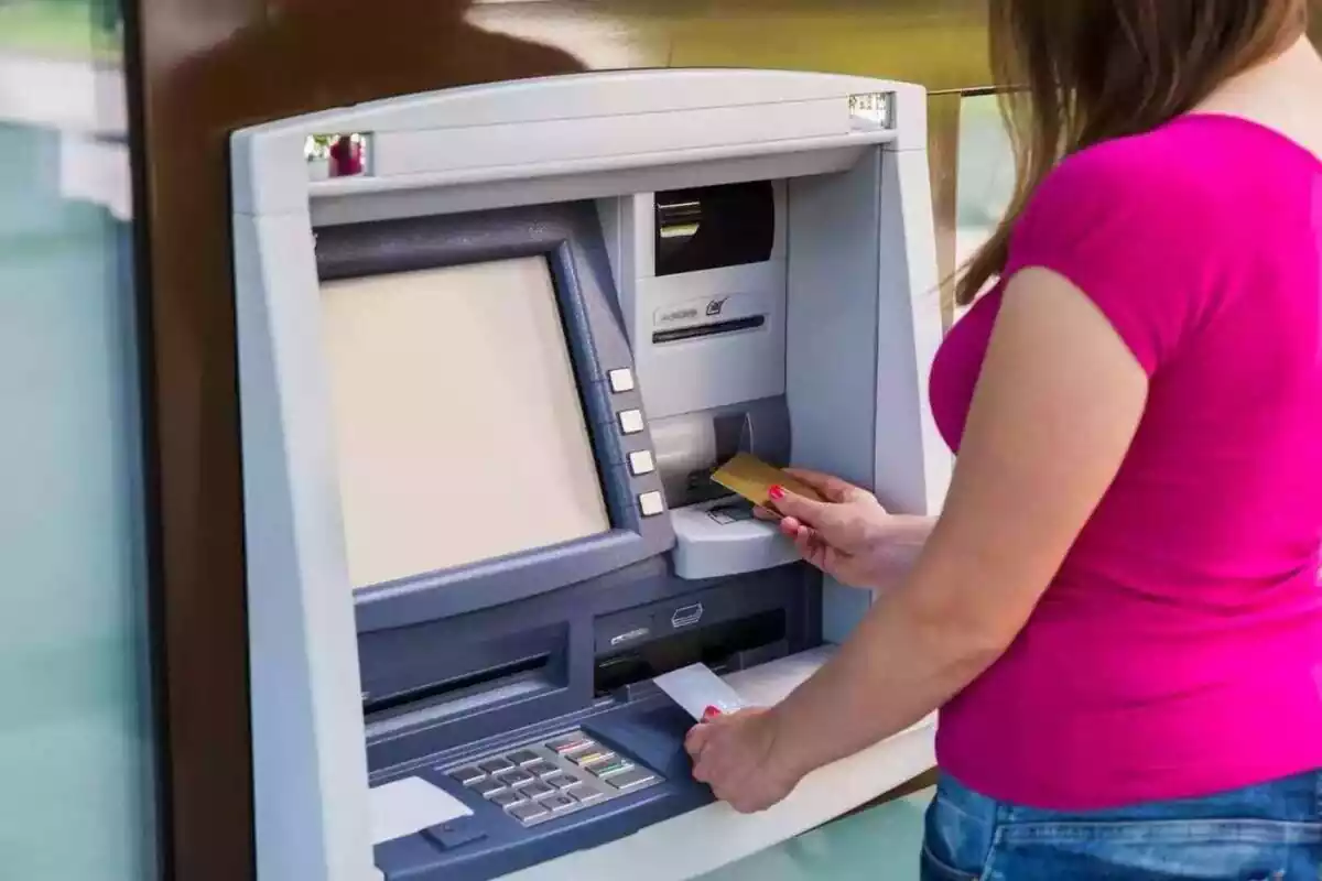 Dona introduint una targeta de crèdit en un caixer automàtic