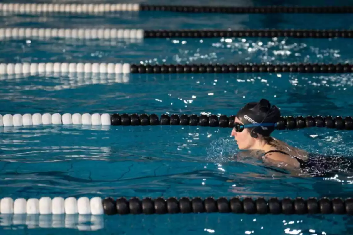 Una dona nedant en una piscina amb carrils dividits per boles negres i blanques
