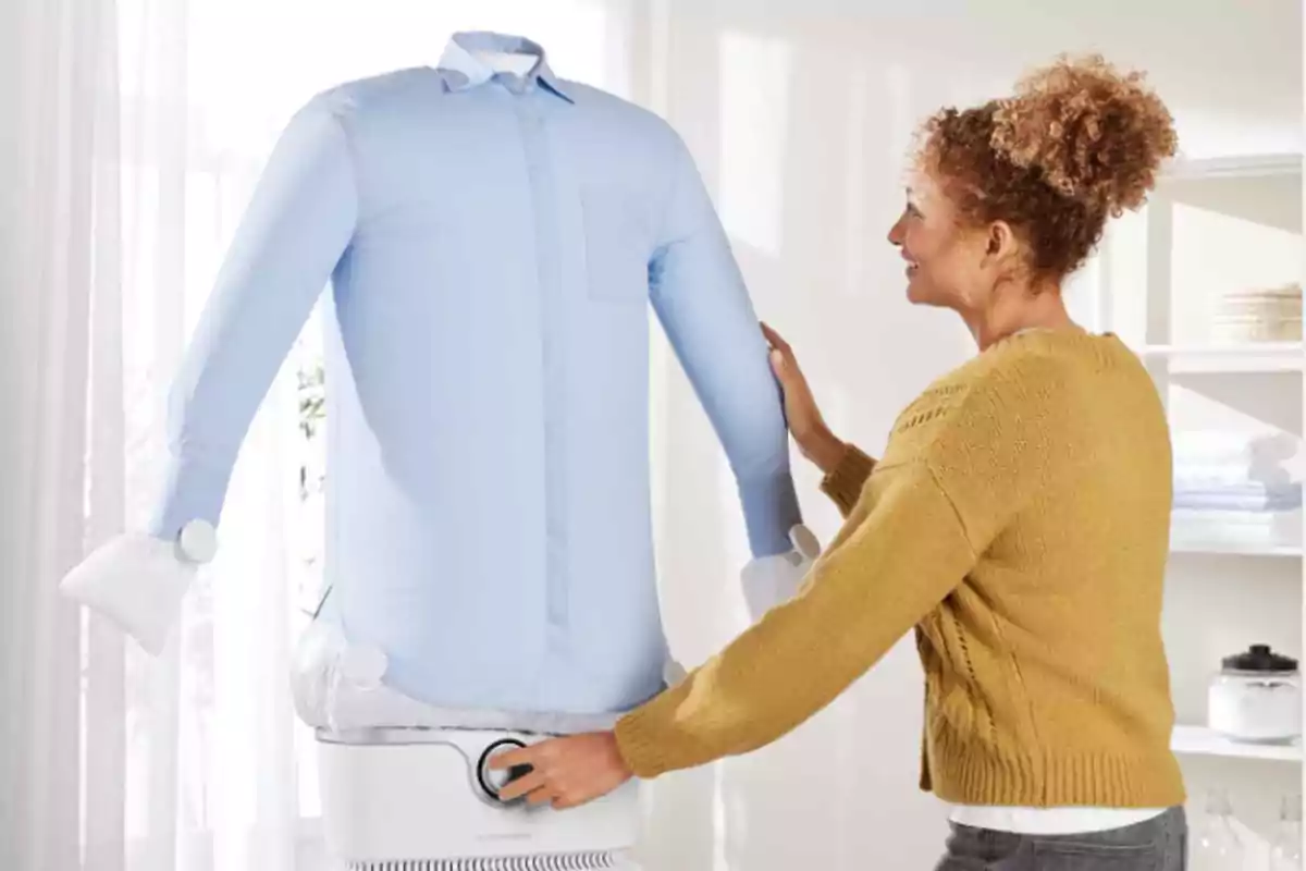 Dona utilitzant un maniquí inflable per assecar i planxar una camisa blava en una habitació il·luminada Dona utilitzant un maniquí inflable per assecar i planxar una camisa blava en una habitació il·luminada