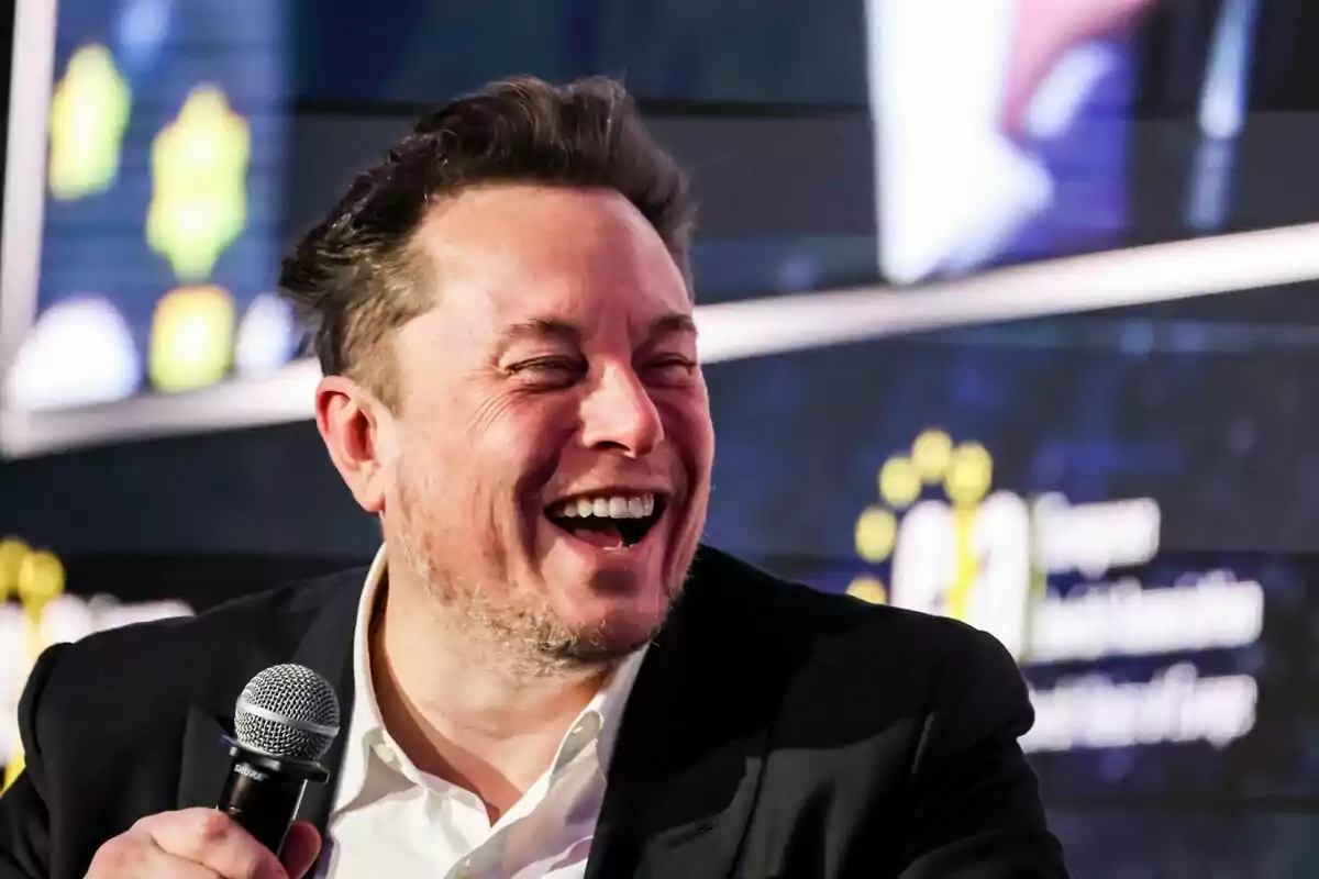 Elon Musk somrient mentre sosté un micròfon en un esdeveniment. Elon Musk somrient mentre sosté un micròfon en un esdeveniment.