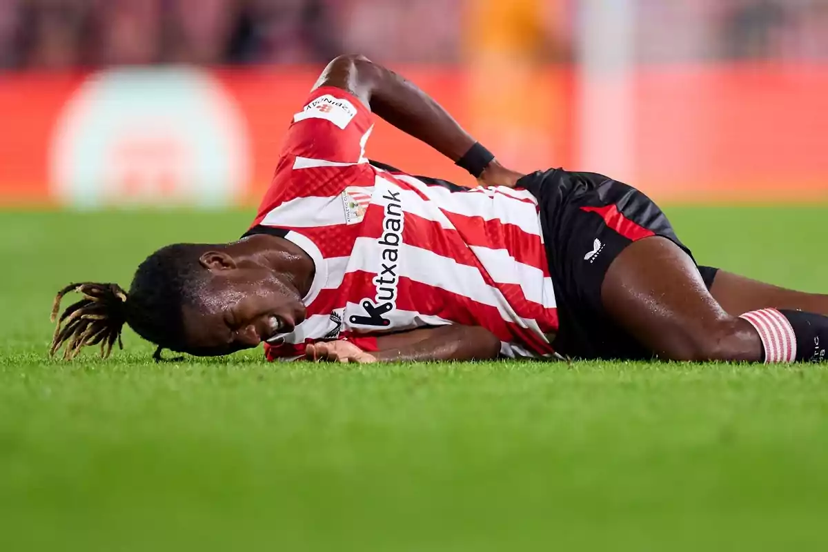Soccer player in red and white uniform lying on the grass with a pained expression. Soccer player in red and white uniform lying on the grass with a pained expression.