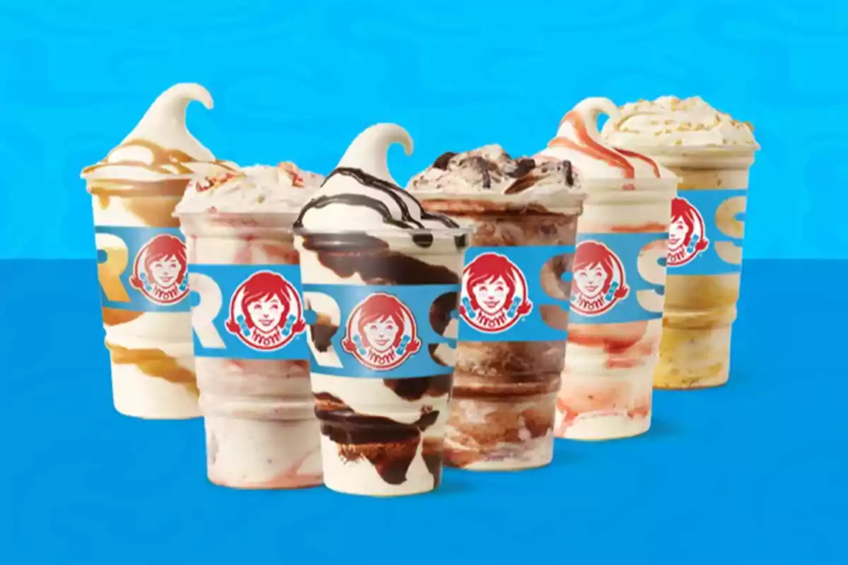 Cinco vasos de helado con diferentes sabores y coberturas, con un fondo azul y el logo de una cadena de comida rápida en cada vaso. Cinco vasos de helado con diferentes sabores y coberturas, con un fondo azul y el logo de una cadena de comida rápida en cada vaso.