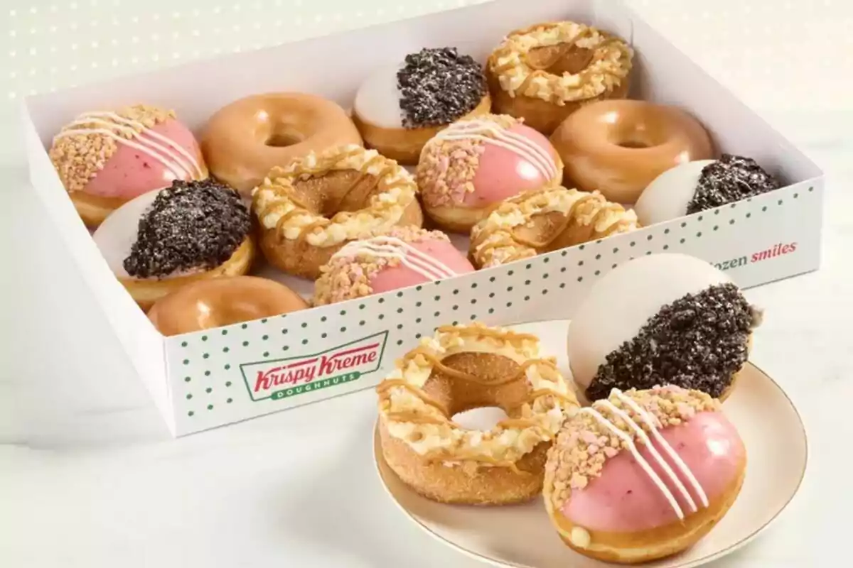 A box of assorted Krispy Kreme donuts with different toppings and glazes, including classic glazed donuts, strawberry-covered donuts with sprinkles, and chocolate-covered donuts with cookie crumbs, presented on a plate and in a box. A box of assorted Krispy Kreme donuts with different toppings and glazes, including classic glazed donuts, strawberry-covered donuts with sprinkles, and chocolate-covered donuts with cookie crumbs, presented on a plate and in a box.