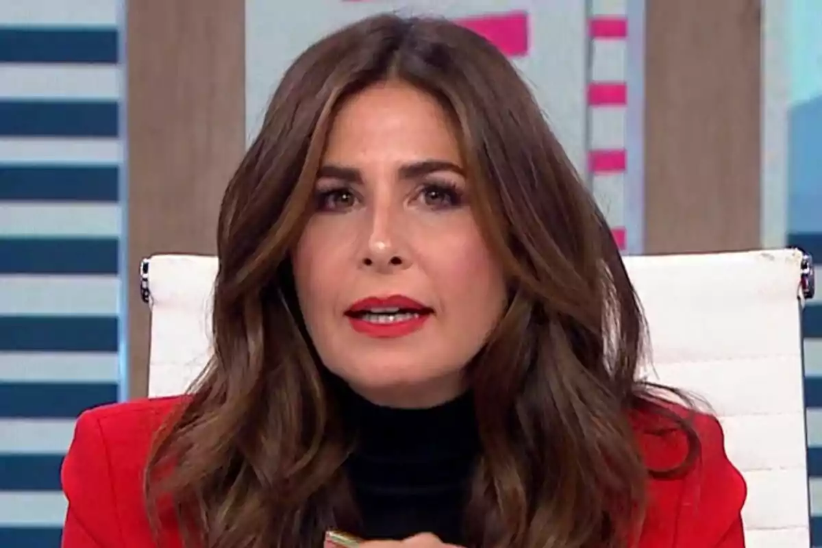 Nuria Roca con cabello largo y castaño lleva un atuendo rojo y negro mientras está sentada en una silla blanca en La Roca.