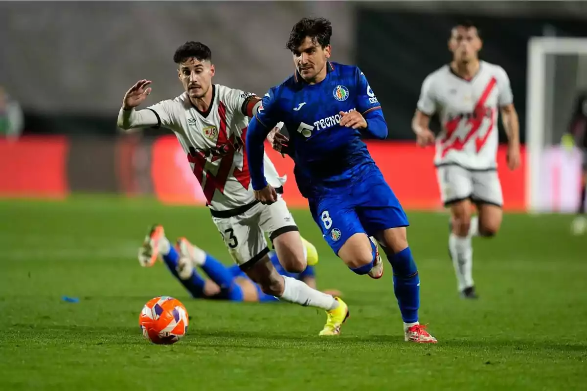 Jugadores de fútbol compiten por el balón en un partido.