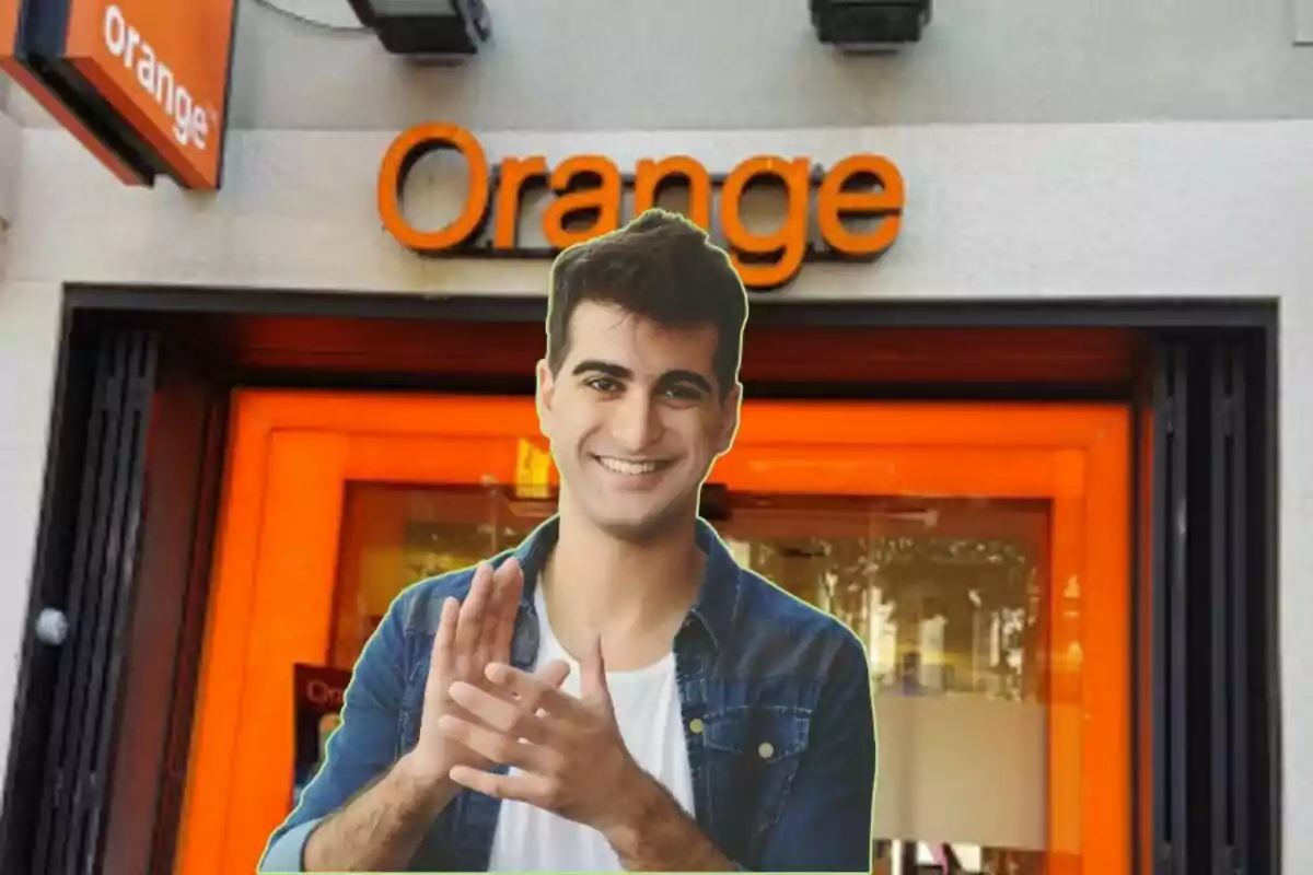 Un home somrient amb una camisa de mezclilla és davant d'una botiga d'Orange.