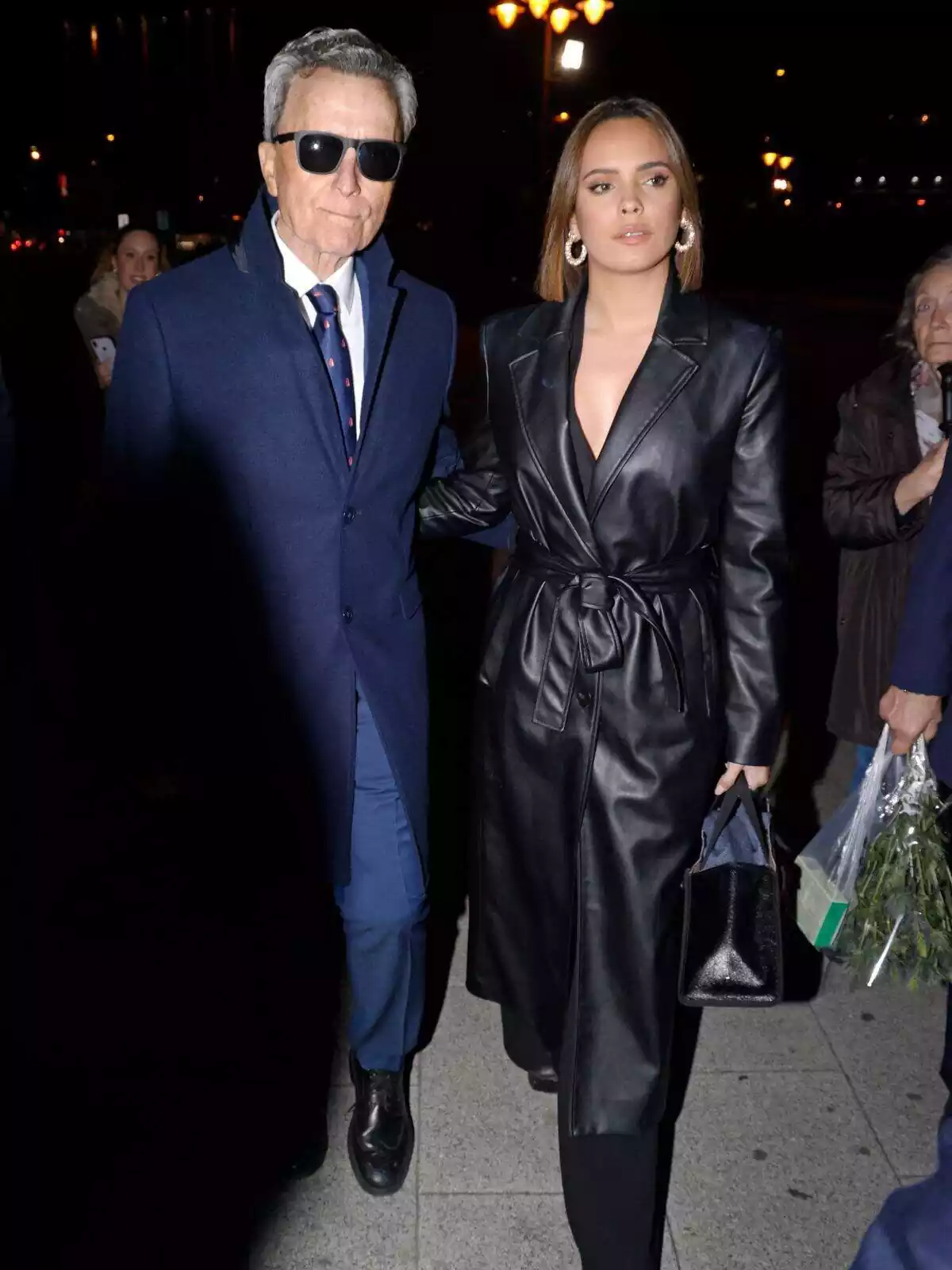 José Ortega Cano amb ulleres de sol i corbata blava, i Gloria Camila Ortega seria amb una gavardina negra