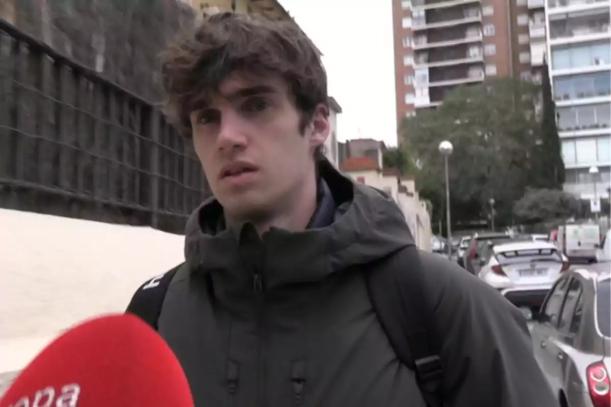 Pablo Urdangarin amb jaqueta fosca i motxilla és entrevistat en un carrer urbà amb edificis i cotxes al fons. Pablo Urdangarin amb jaqueta fosca i motxilla és entrevistat en un carrer urbà amb edificis i cotxes al fons.