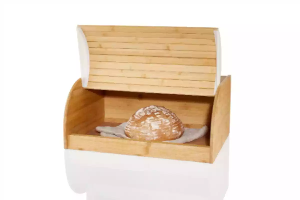 Panera de fusta oberta amb un pa rodó a l’interior sobre un drap blanc Panera de fusta oberta amb un pa rodó a l’interior sobre un drap blanc