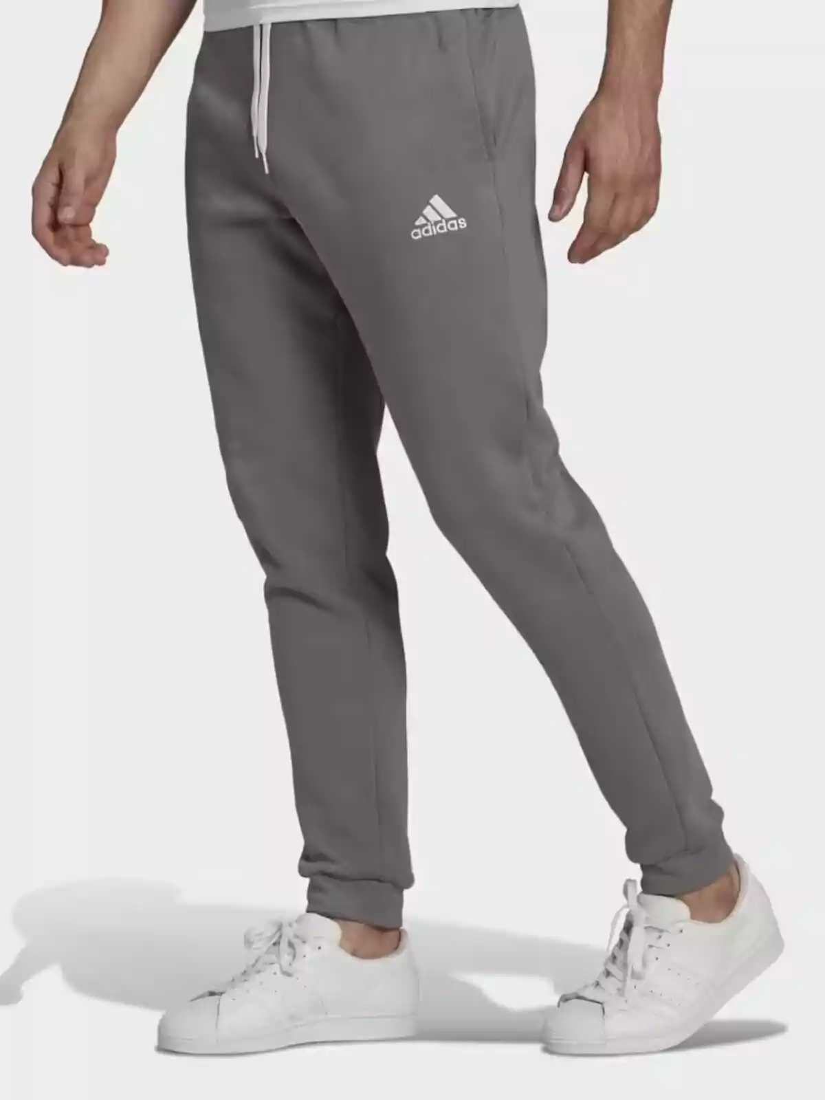 Home vestint pantalons esportius grisos d'Adidas i sabatilles blanques.