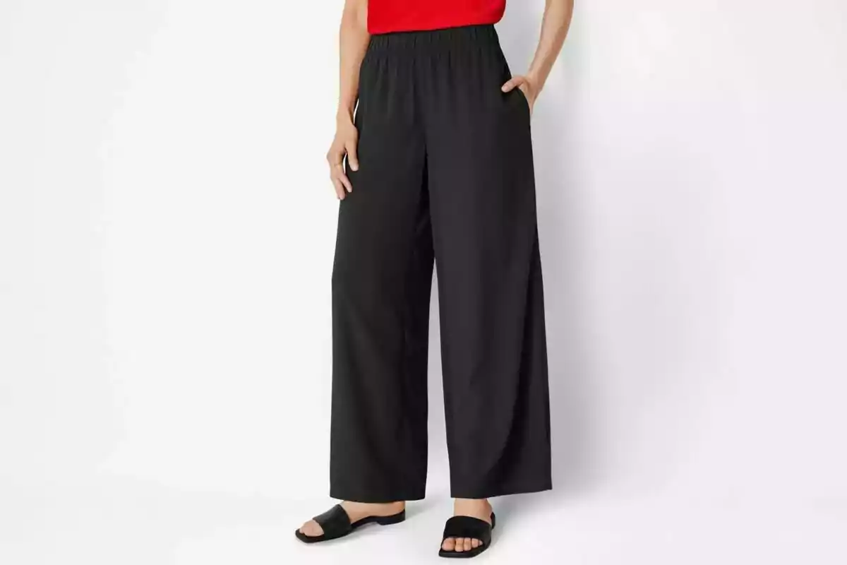 Persona vestint uns pantalons negres de cama ampla de Lidl amb una brusa vermella i sandàlies negres. Persona vestint uns pantalons negres de cama ampla de Lidl amb una brusa vermella i sandàlies negres.