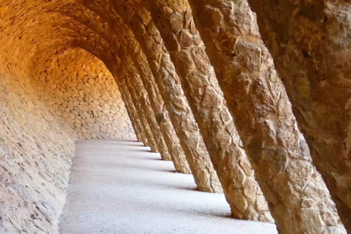 Pasillo curvo de piedra con arcos inclinados y suelo de grava
