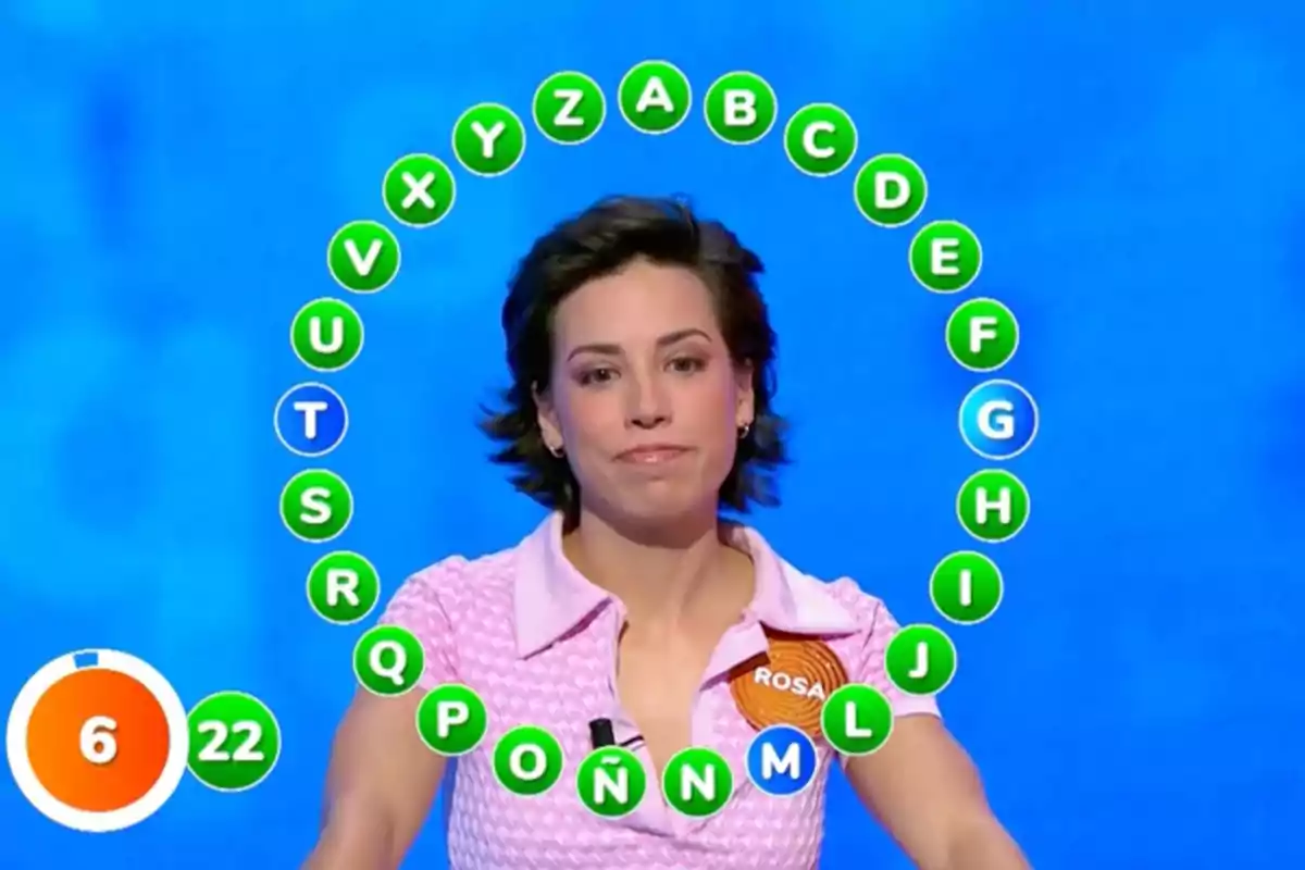 Rosa participant en un concurs de televisió amb un cercle de lletres al voltant i un cronòmetre a la cantonada inferior esquerra. Captura de 'Pasapalabra'. Rosa participant en un concurs de televisió amb un cercle de lletres al voltant i un cronòmetre a la cantonada inferior esquerra. Captura de 'Pasapalabra'.