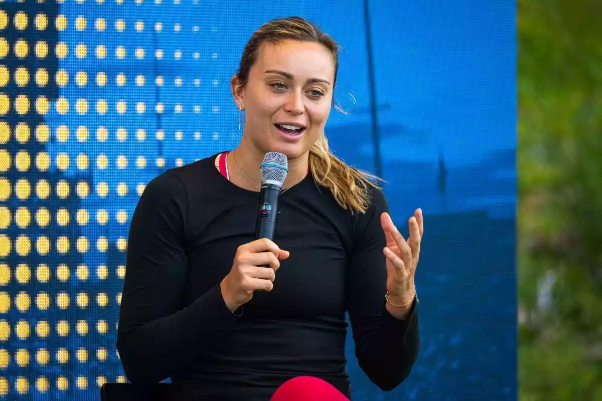 Paula Badosa speaking at a press conference with a microphone in her hand Paula Badosa speaking at a press conference with a microphone in her hand