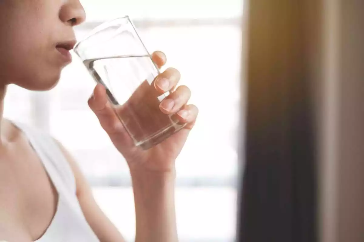 Mitja cara d'una dona bebent aigua