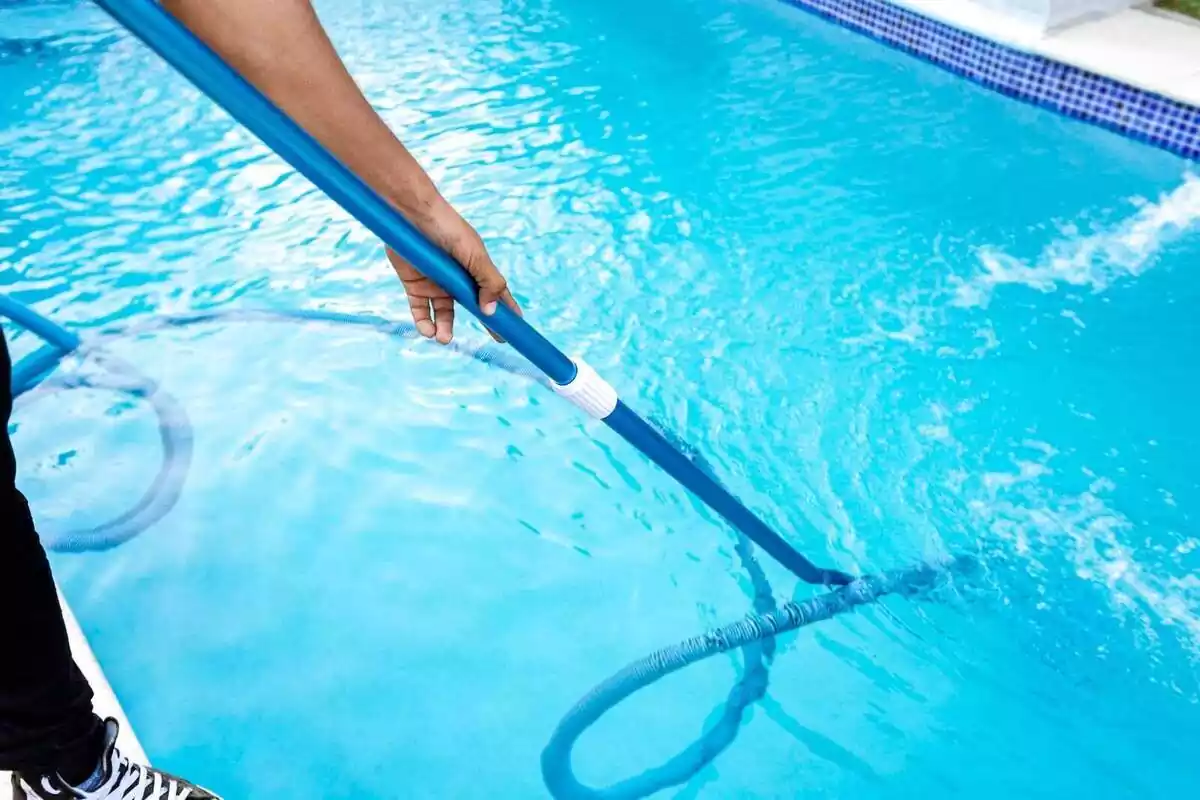 Pla curt del braç d'una persona adulta netejant el fons d'una piscina