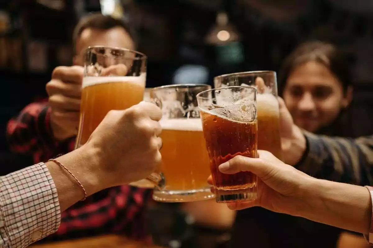 Grup de persones brindant amb gerres de cervesa en un bar