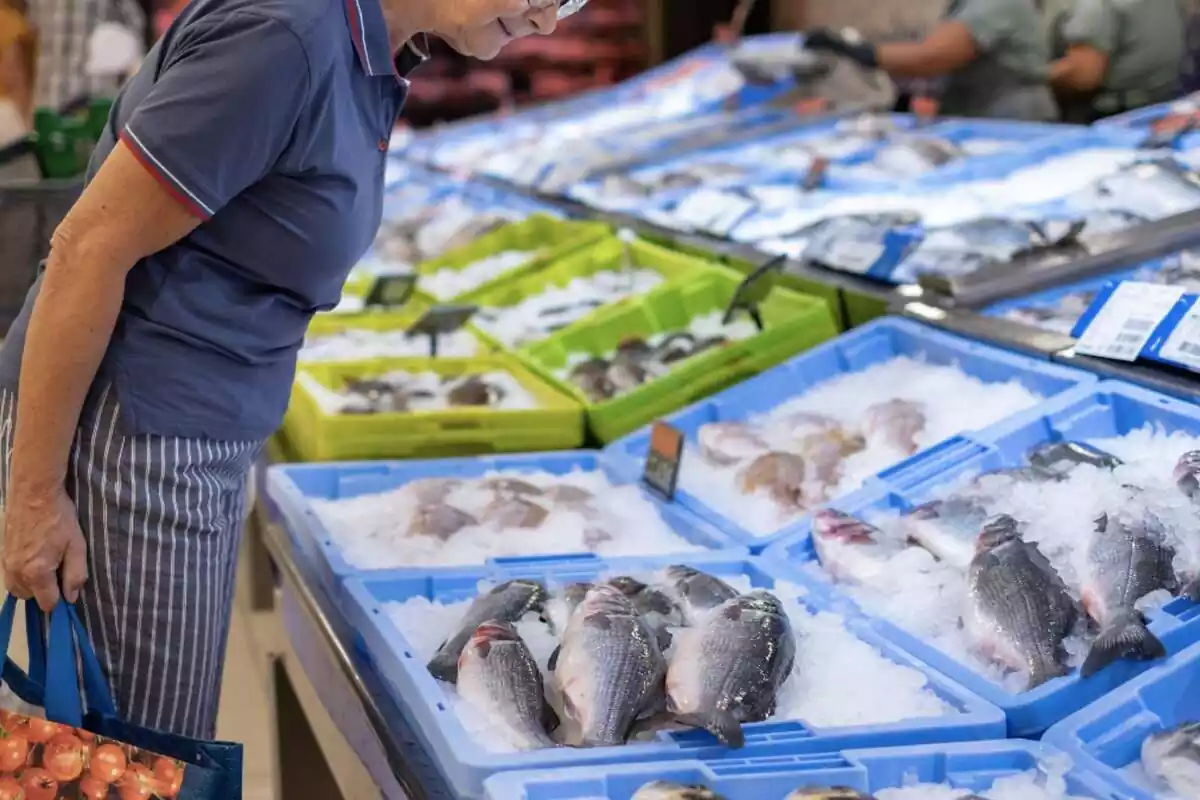 Mujer mirando los pescados a la venta en un supermercado de Mercadona