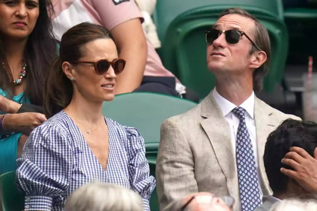 People sitting at an outdoor sporting event, wearing sunglasses and looking up. People sitting at an outdoor sporting event, wearing sunglasses and looking up.