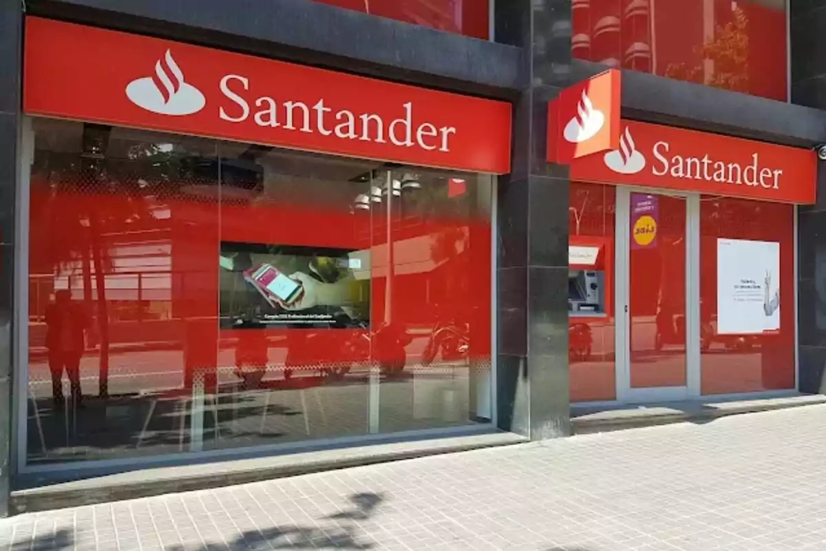 Façana d'una sucursal del banc Santander amb rètols vermells i blancs.