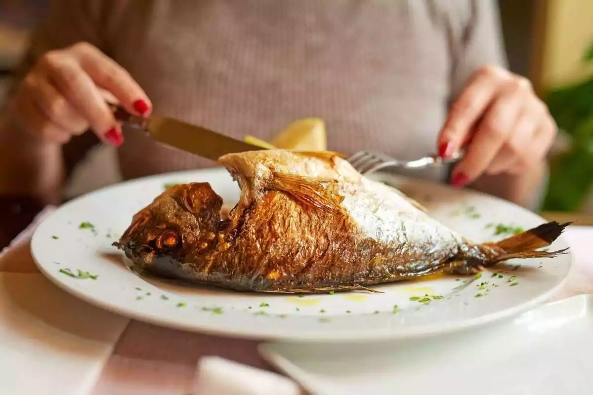 Pla d'una persona tallant peix a un restaurant