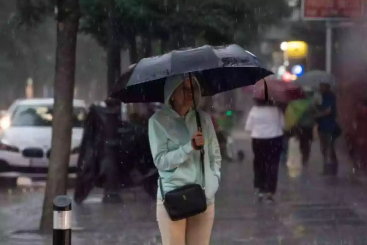 Una dona amb un paraigua sota la pluja