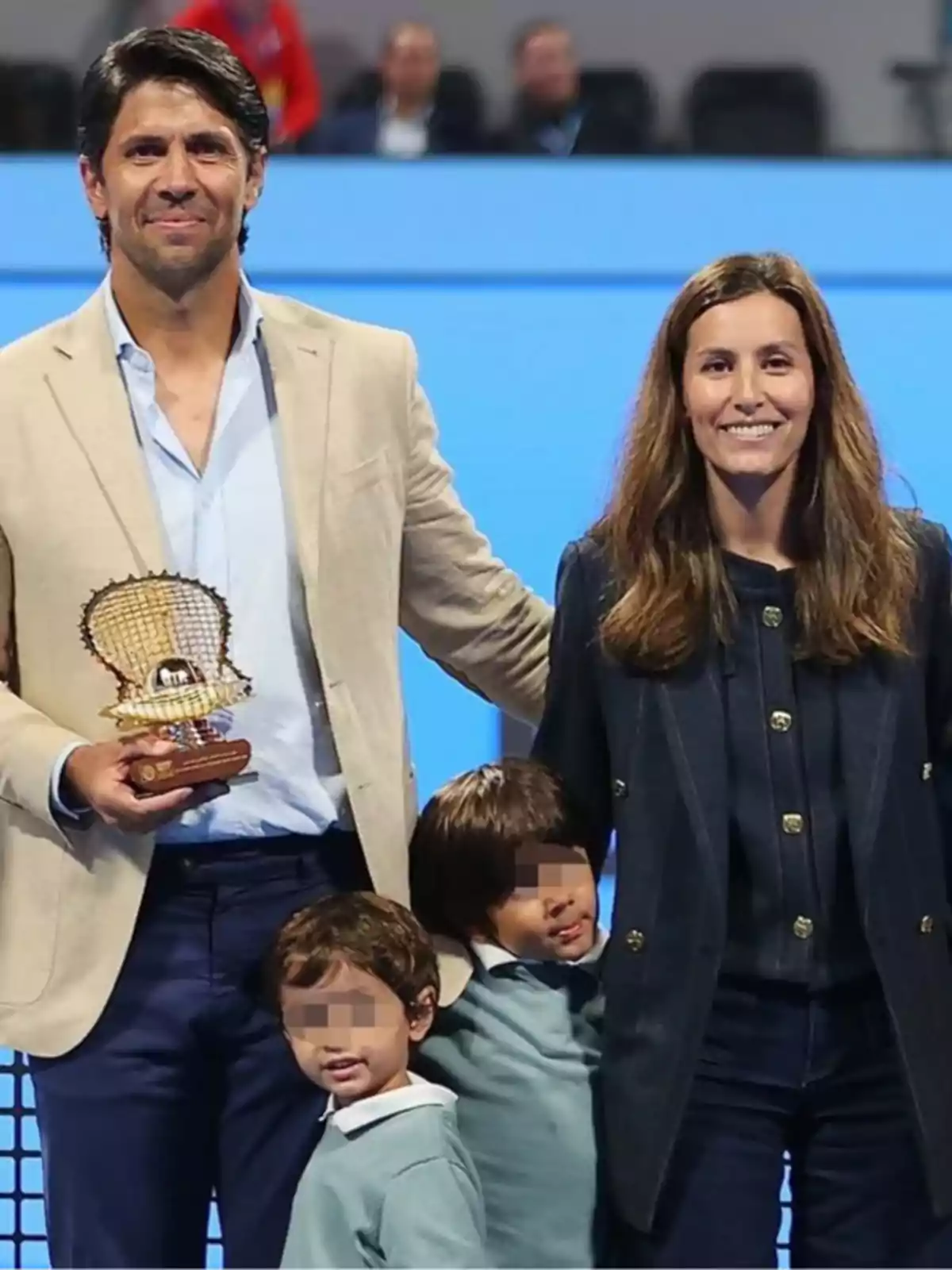 Ana Boyer, Fernando Verdasco i els seus fills posen junts en un esdeveniment esportiu, l'home sosté un trofeu i les cares dels nens estan pixelades. Ana Boyer, Fernando Verdasco i els seus fills posen junts en un esdeveniment esportiu, l'home sosté un trofeu i les cares dels nens estan pixelades.
