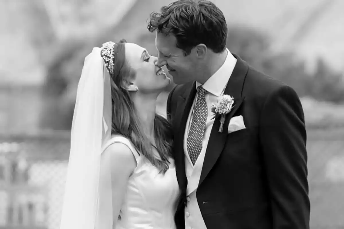 Johnny Thompson i Olivia Lewis, acabats de casar, somrient i tocant-se els nassos en una foto en blanc i negre Johnny Thompson i Olivia Lewis, acabats de casar, somrient i tocant-se els nassos en una foto en blanc i negre