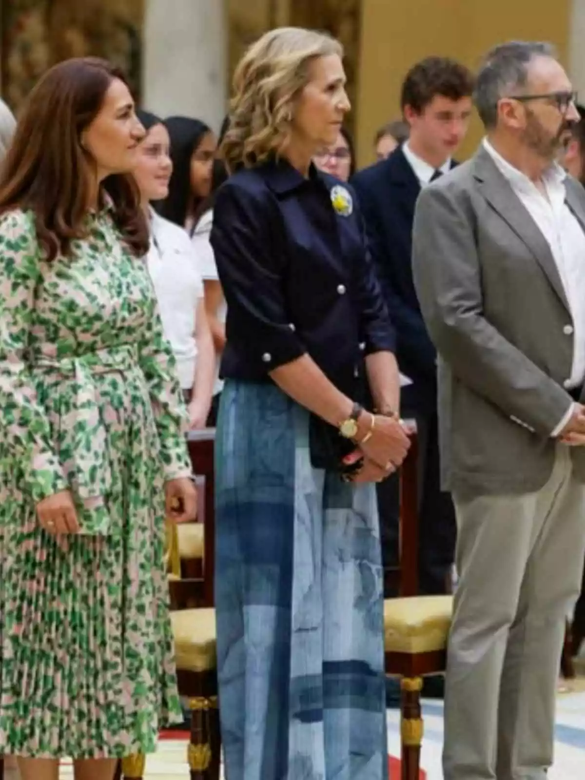 La infanta Elena i dues persones més dretes en un esdeveniment formal, dues dones i un home, amb diverses persones al fons. La infanta Elena i dues persones més dretes en un esdeveniment formal, dues dones i un home, amb diverses persones al fons.