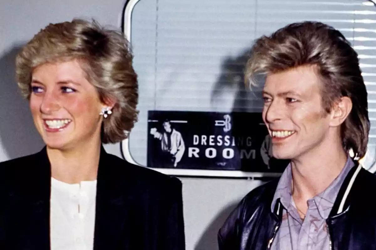 Lady Di i David Bowie somrients posen davant d'un cartell que diu Lady Di i David Bowie somrients posen davant d'un cartell que diu