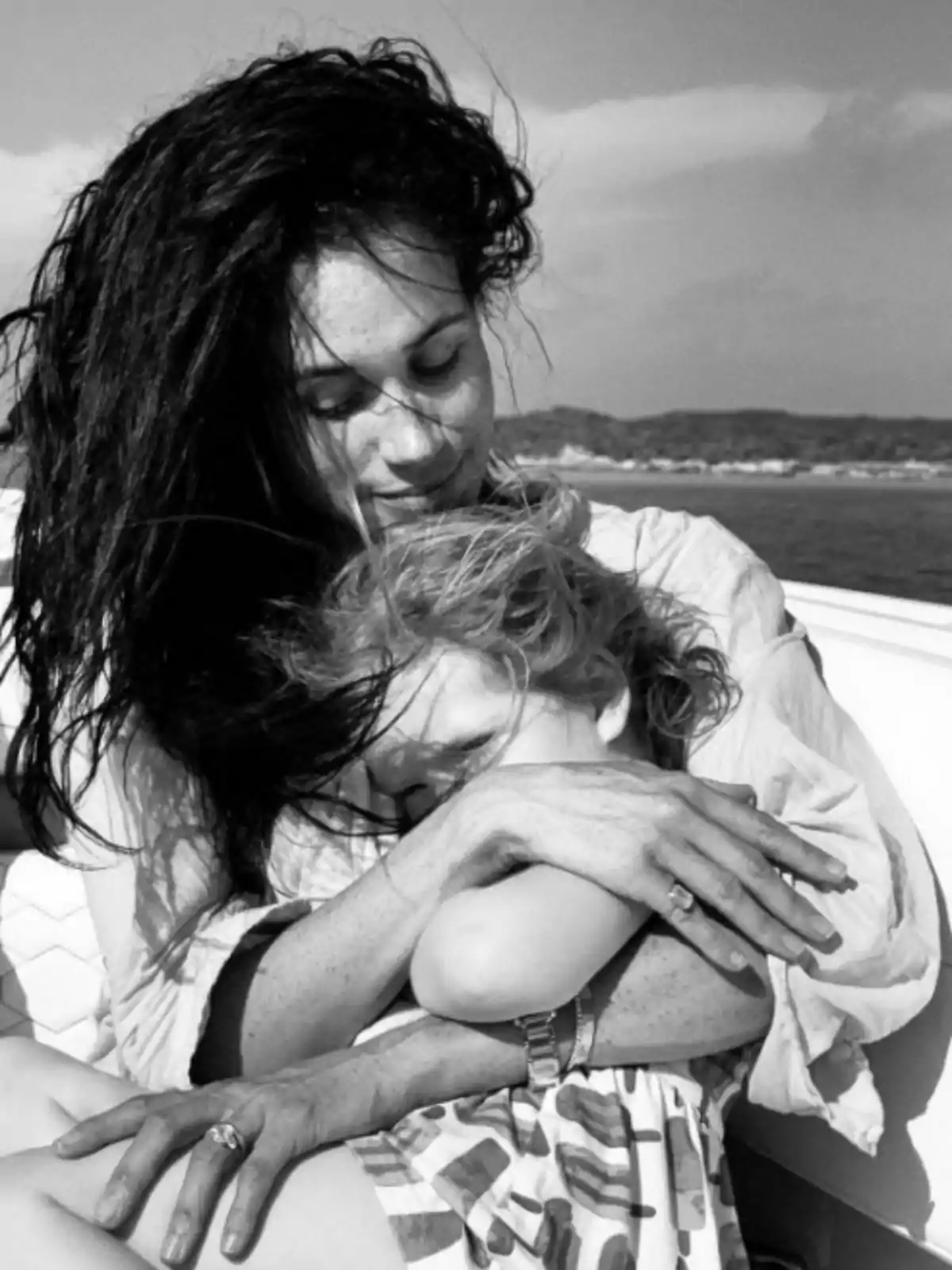 Meghan Markle tenderly hugging a little girl while they sit outdoors on a sunny day Meghan Markle tenderly hugging a little girl while they sit outdoors on a sunny day