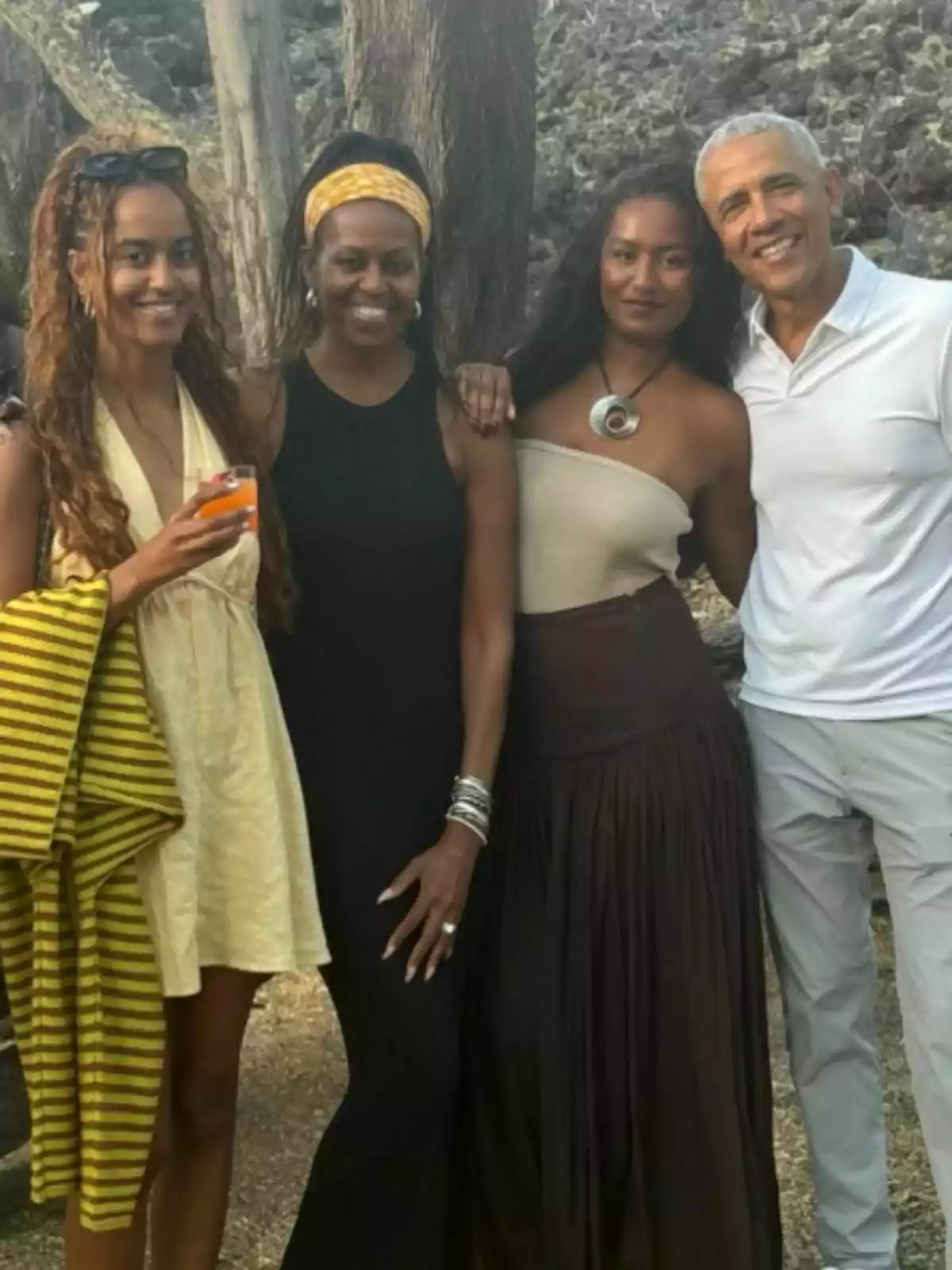 Malia, Michelle, Sasha, and Barack Obama pose together outdoors, smiling and hugging, with trees and rocks in the background. Malia, Michelle, Sasha, and Barack Obama pose together outdoors, smiling and hugging, with trees and rocks in the background.