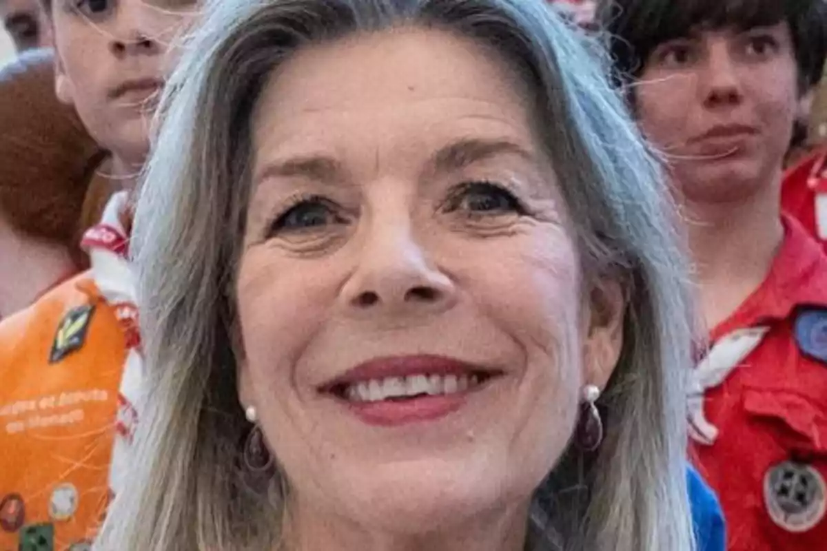 Carolina de Mònaco somrient amb cabell canós i arracades, envoltada de persones amb uniformes d'escoltes.