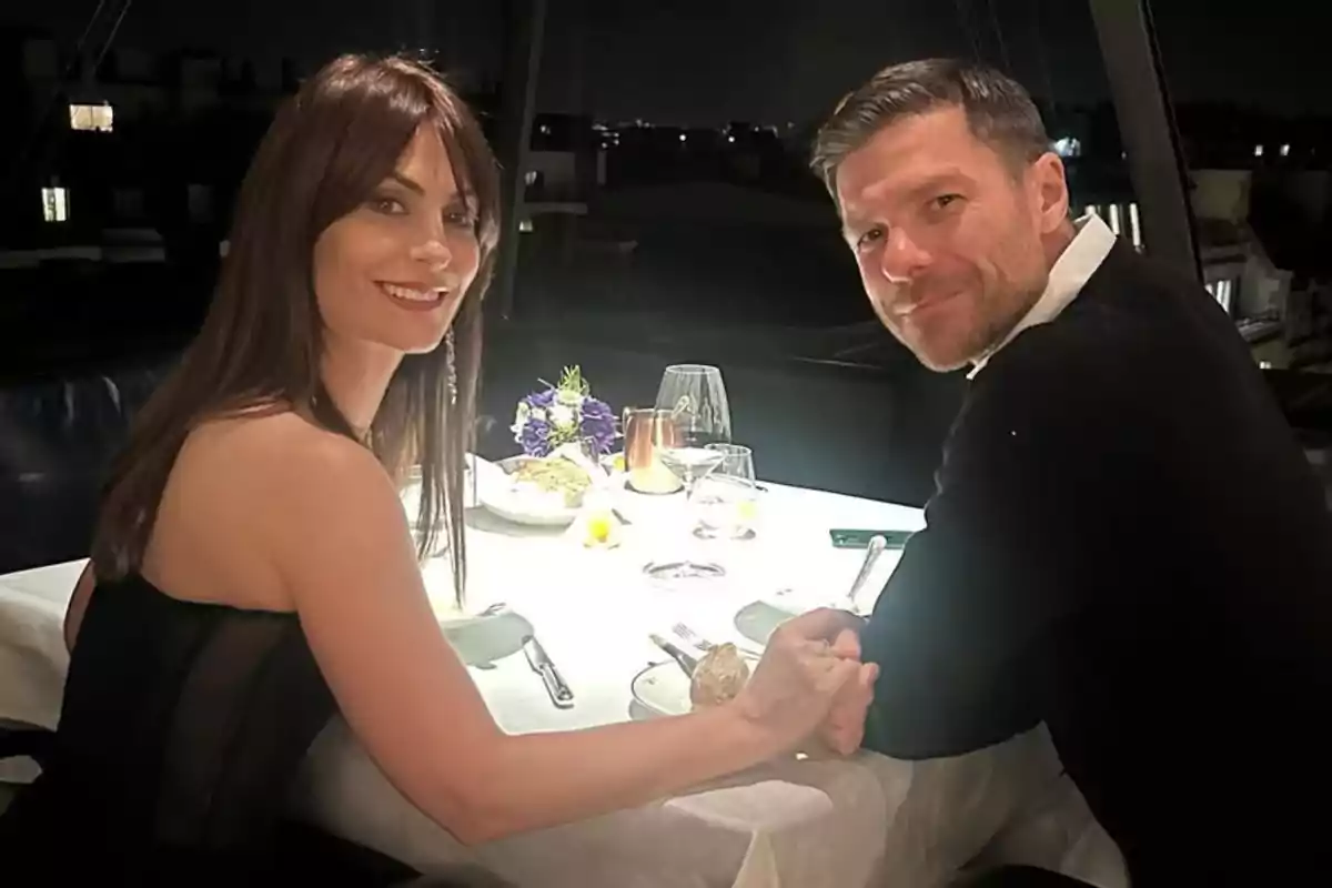 Nagore Aranburu i Xabi Alonso asseguts a una taula de restaurant elegantment decorada, agafats de les mans i somrient a la càmera. Nagore Aranburu i Xabi Alonso asseguts a una taula de restaurant elegantment decorada, agafats de les mans i somrient a la càmera.