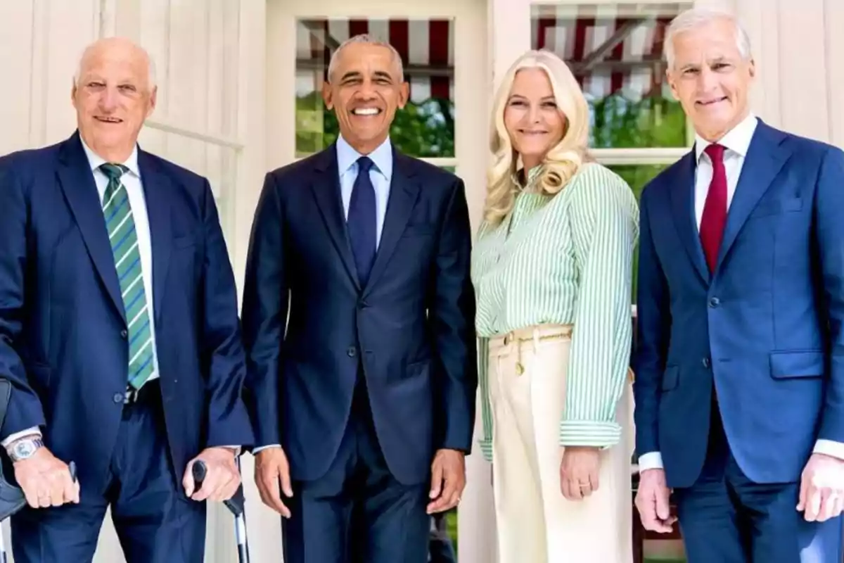 A group of four formally dressed people posing in front of a building with windows. A group of four formally dressed people posing in front of a building with windows.