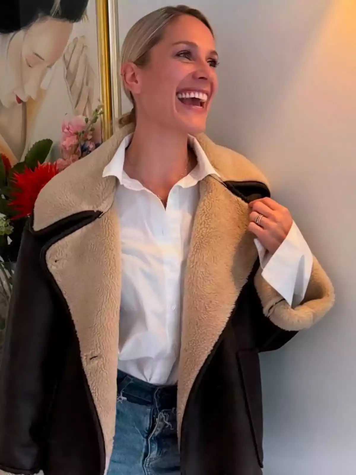 Pascalle Paerel somrient amb una jaqueta de pell sintètica i camisa blanca, dempeus al costat d'una pintura i flors. Pascalle Paerel somrient amb una jaqueta de pell sintètica i camisa blanca, dempeus al costat d'una pintura i flors.