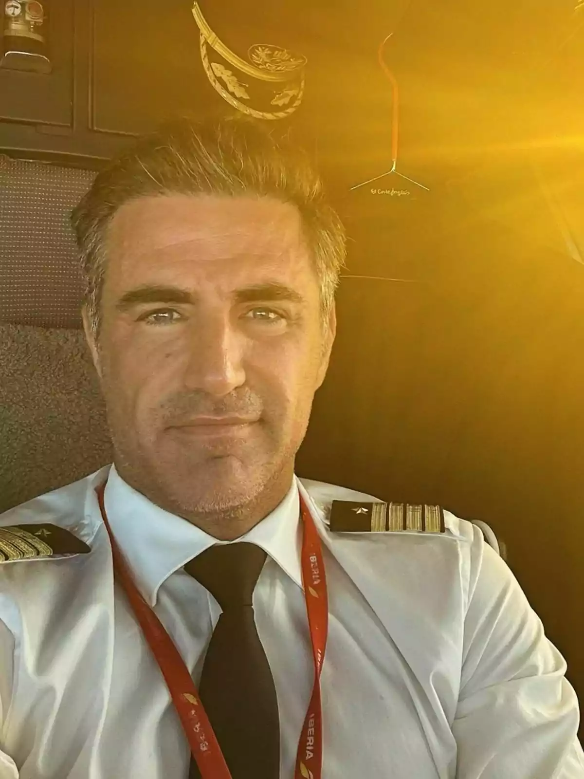 Perico Durán amb uniforme i corbata negra està assegut a la cabina d'un avió amb llum daurada il·luminant l'espai.