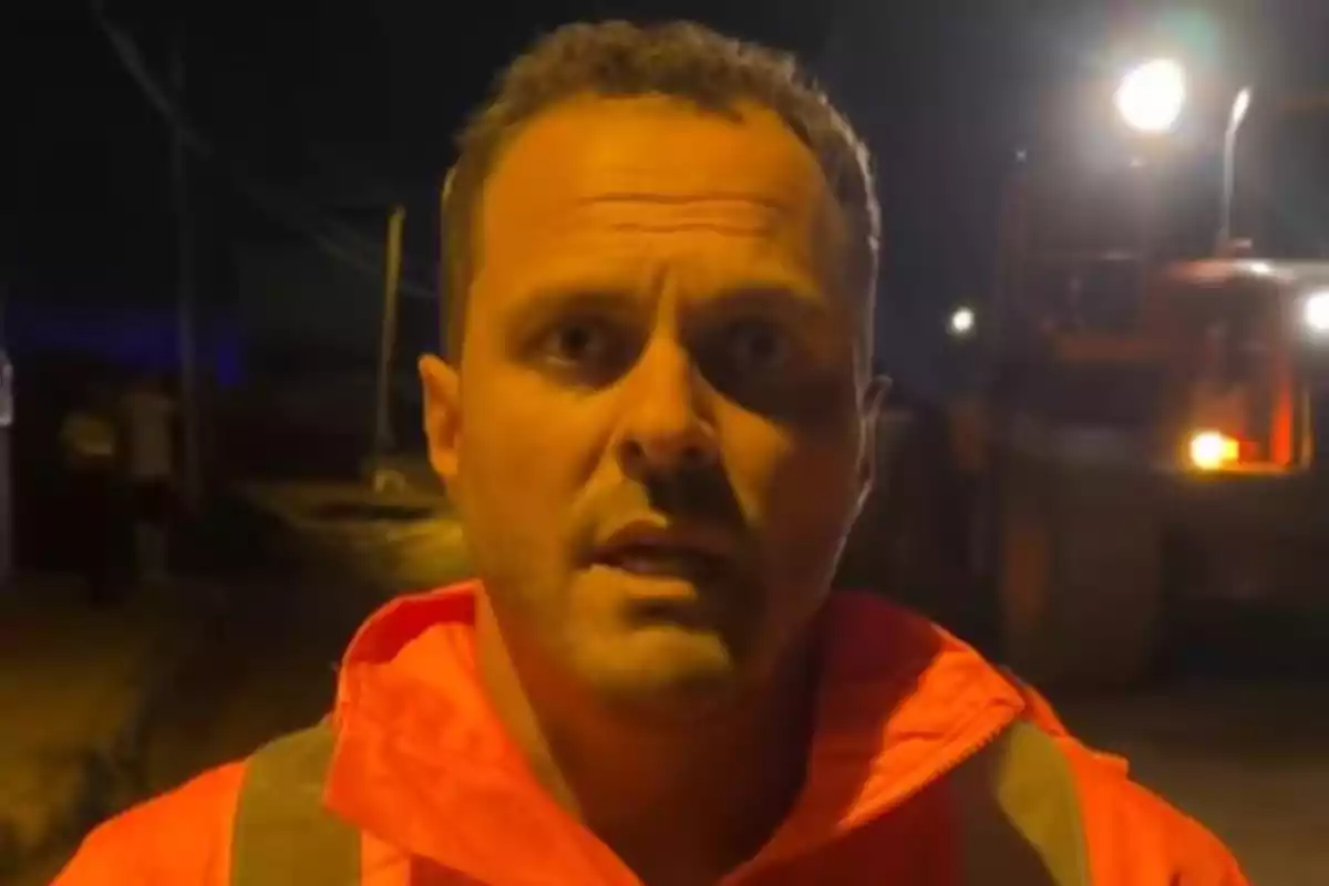 Yonathan de León amb jaqueta taronja està dret en un carrer fosc il·luminat per llums brillants al fons. Yonathan de León amb jaqueta taronja està dret en un carrer fosc il·luminat per llums brillants al fons.