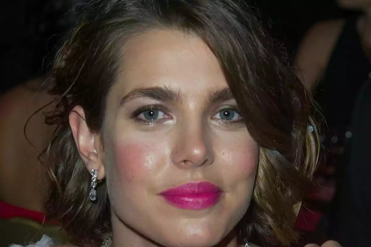 Close-up of Carlota Casiraghi with a serious expression, wearing pink lipstick and shiny earrings. Close-up of Carlota Casiraghi with a serious expression, wearing pink lipstick and shiny earrings.
