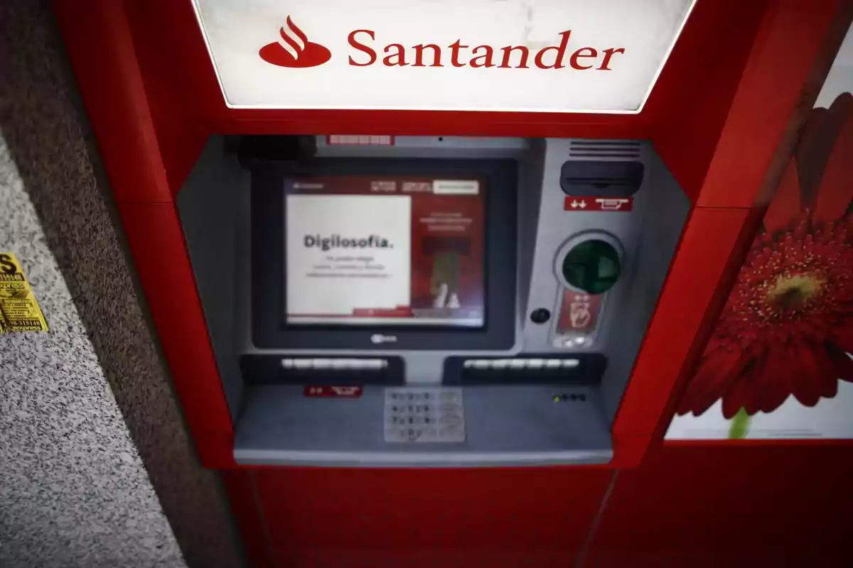 Caixer automàtic del banc Santander amb pantalla encesa i teclat numèric visible.