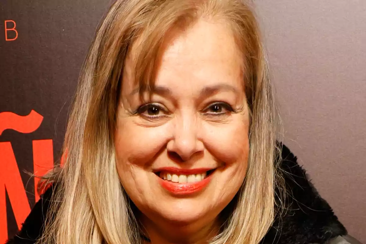 Emma Ozores somrient davant d'un fons fosc amb lletres vermelles.