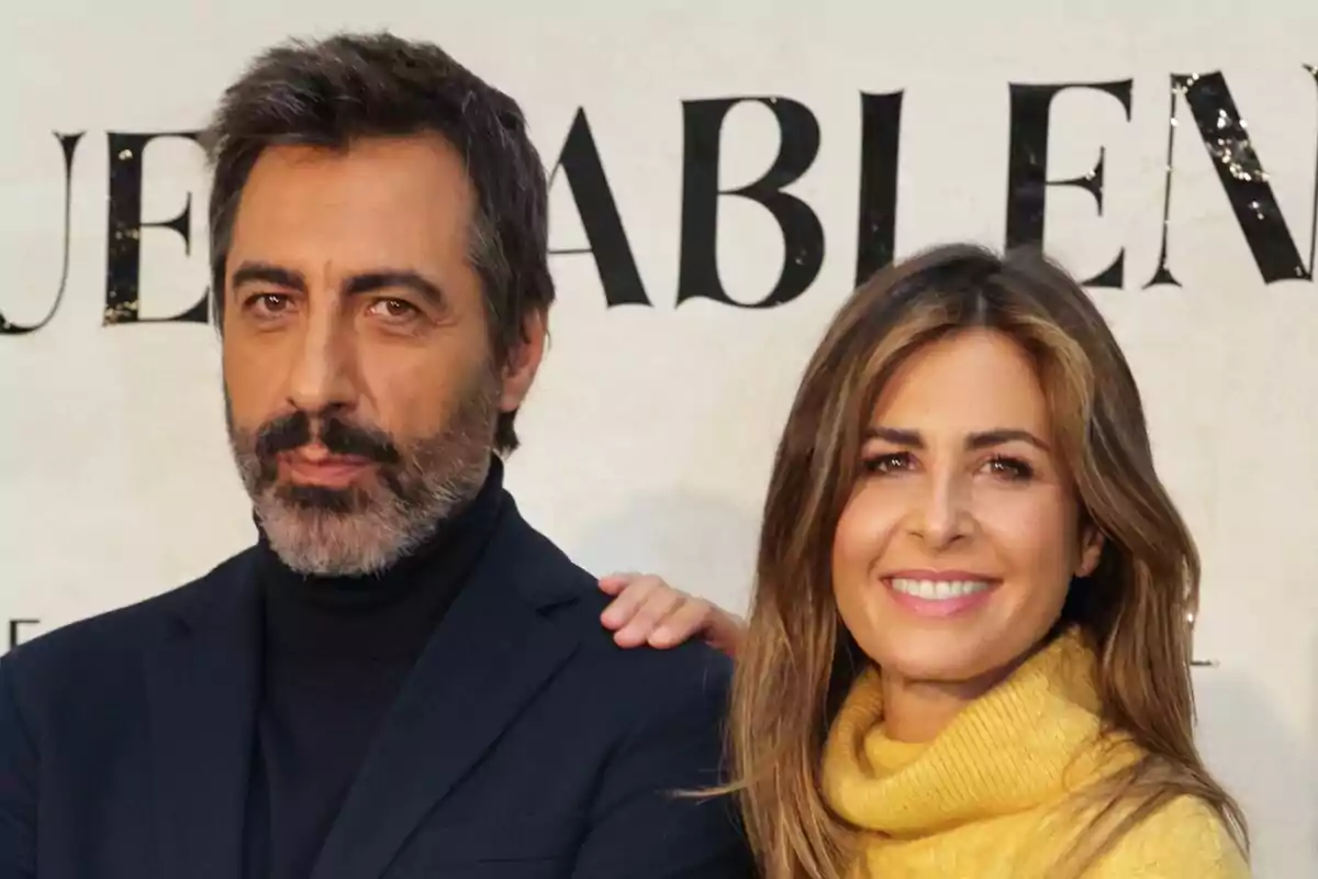 Nuria Roca somrient amb la mà sobre l'espatlla de Juan del Val amb barba i expressió seriosa, tots dos posant davant d'un fons amb text.