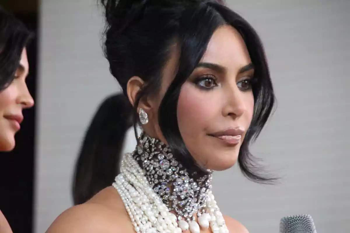 Kim Kardashian with an elaborate pearl and jewelry necklace, dark hair up, and elegant makeup. Kim Kardashian with an elaborate pearl and jewelry necklace, dark hair up, and elegant makeup.